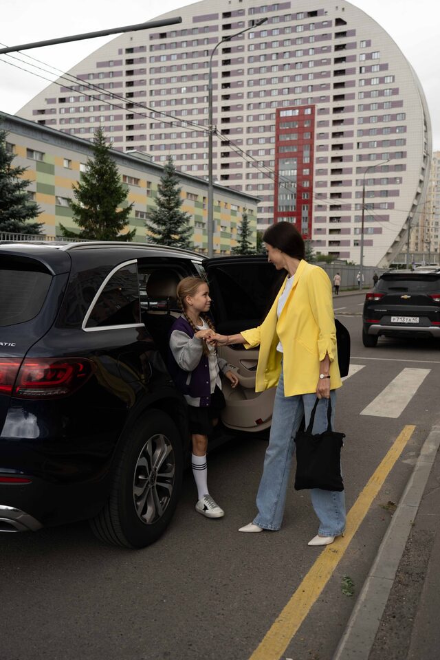 Автоняня помогает девочке выйти из машины на тротуар